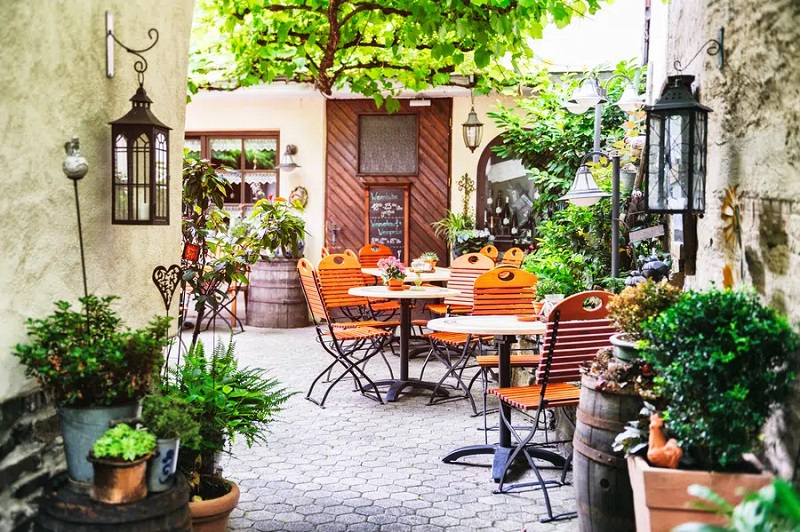 تراس کافه‌ای با گل‌ها و گیاهان در شهر کوچک اروپایی