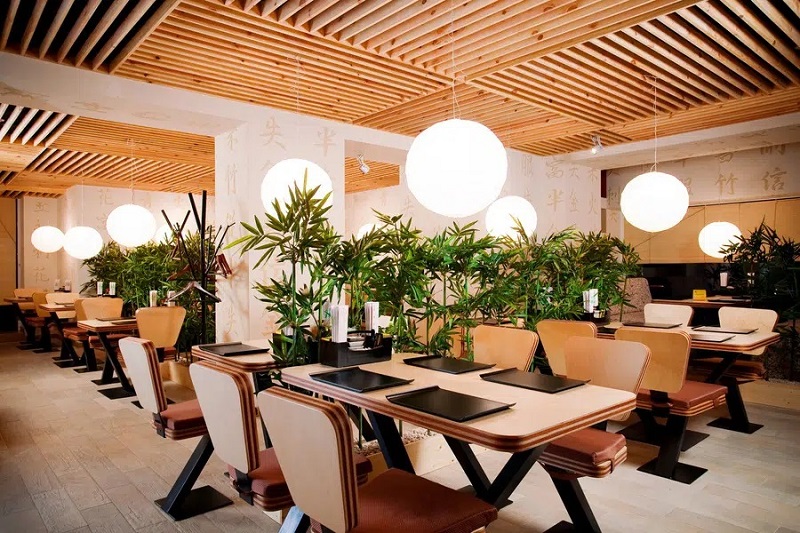 فضای داخلی یک رستوران با ترکیب گیاهان و لامپ‌های آویز