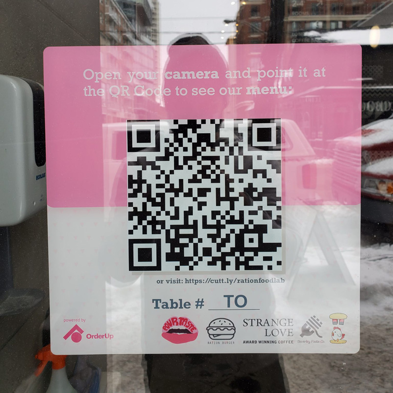 کارت حاوی کد QR منوی دیجیتال یک رستوران که روی شیشه چسبانده شده است