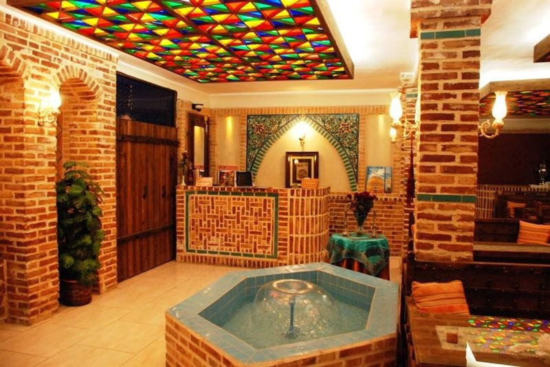 تصویر فضای داخلی سفره خانه سنتی ترنج با نمای آجرهاس سه سانتی و حوضچه