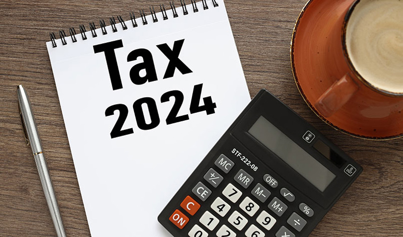 یک ماشین حساب و دفترچه یادداشت با نوشته tax 2024